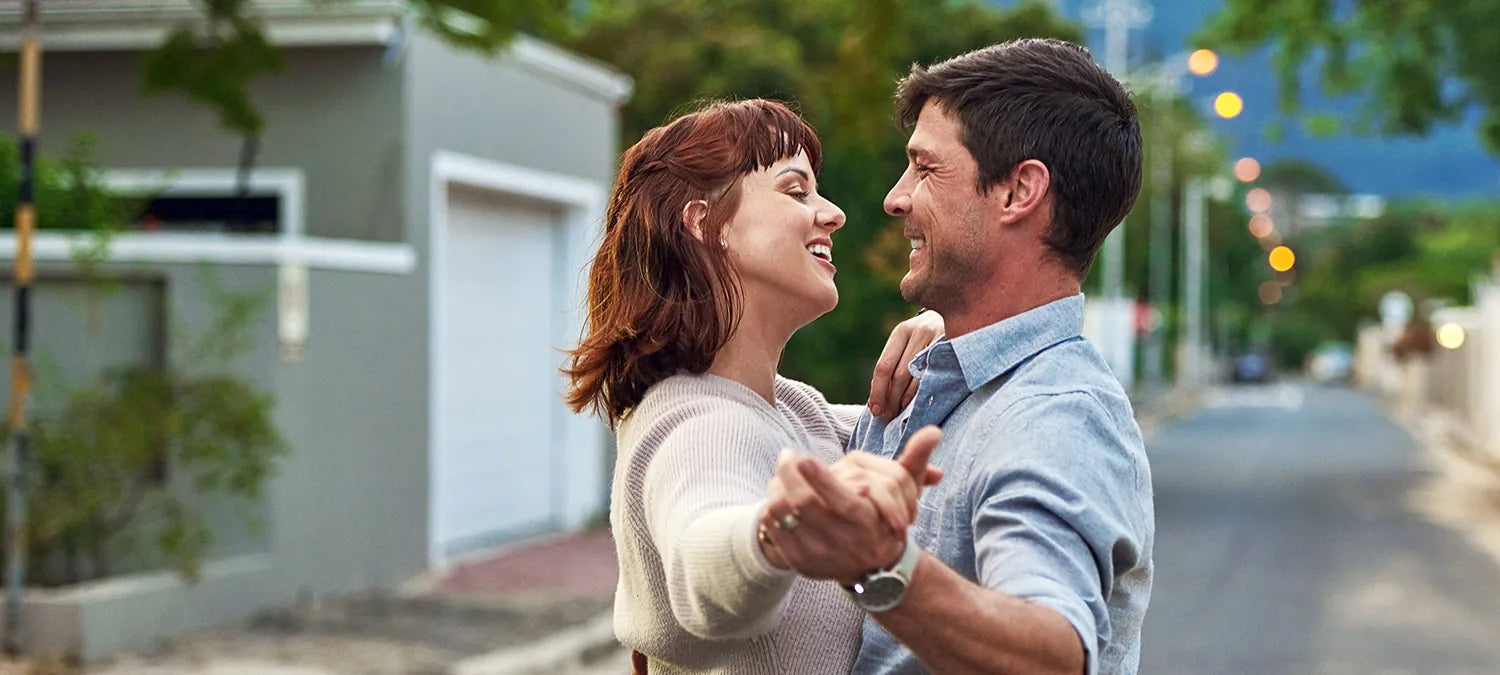 A couple smiling at each other as they dance in a quiet street